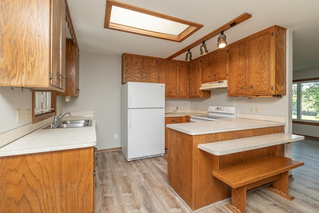 110 Hamilton Dr, River Falls, WI 54022 - kitchen with white appliances, under cabinet range hood, a peninsula, and brown cabinets