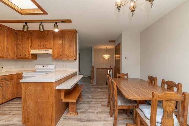 110 Hamilton Dr, River Falls, WI 54022 - kitchen with under cabinet range hood, white range with electric cooktop, light wood-style flooring, brown cabinets, and a chandelier