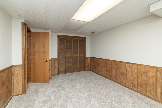 110 Hamilton Dr, River Falls, WI 54022 - unfurnished bedroom featuring wooden walls, wainscoting, a closet, and carpet flooring