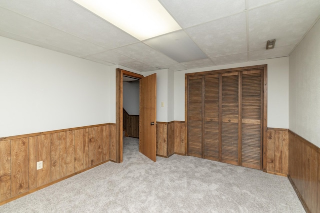 110 Hamilton Dr, River Falls, WI 54022 - unfurnished bedroom with wooden walls, wainscoting, carpet, a closet, and a drop ceiling