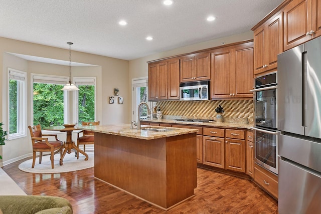 11444 Clarion Way, Minnetonka, MN 55343 - kitchen with appliances with stainless steel finishes, brown cabinetry, light stone counters, recessed lighting, and a textured ceiling
