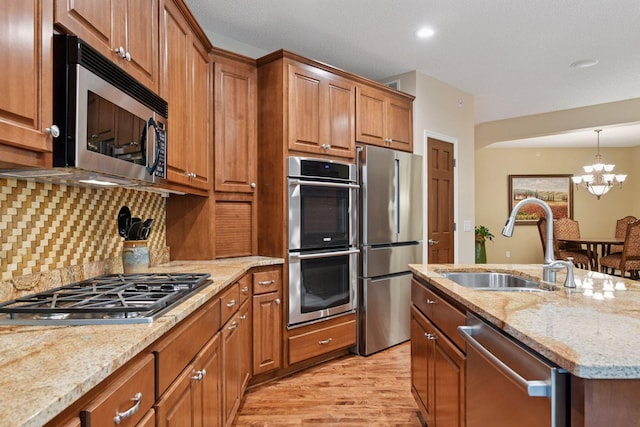 11444 Clarion Way, Minnetonka, MN 55343 - kitchen featuring appliances with stainless steel finishes, light wood finished floors, brown cabinetry, light stone countertops, and a chandelier