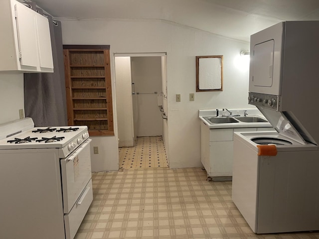77 Morgan St, Tracy, MN 56175 - kitchen with white range with gas cooktop, light floors, stacked washer and clothes dryer, white cabinetry, and lofted ceiling