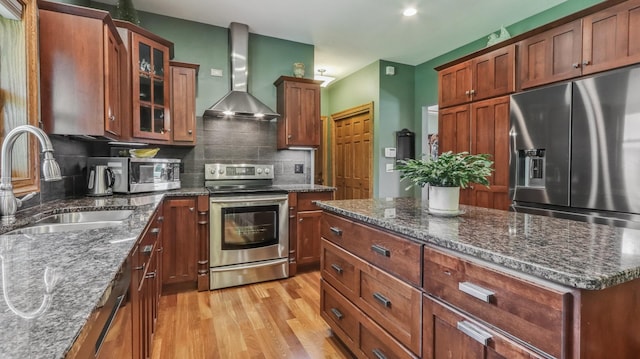 3946 Woodcrest Ct, Eau Claire, WI 54701 - kitchen featuring stainless steel appliances, wall chimney range hood, light wood-style flooring, tasteful backsplash, and glass insert cabinets