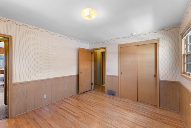 4251 Quincy St NE, Columbia Heights, MN 55421 - unfurnished bedroom with wainscoting, wood finished floors, a closet, wallpapered walls, and wood walls