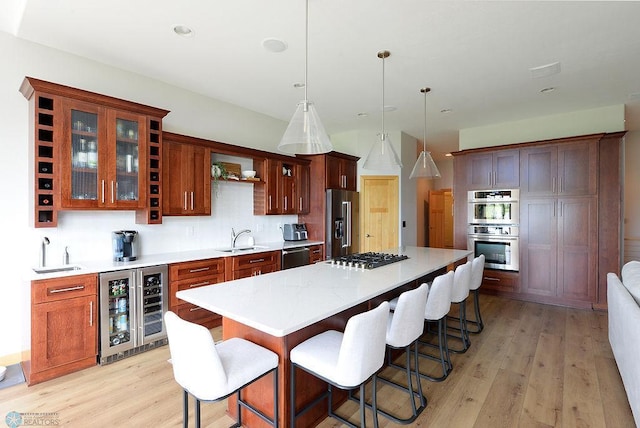 4703 Woodhaven St S, Fargo, ND 58104 - kitchen featuring appliances with stainless steel finishes, beverage cooler, light wood finished floors, and a breakfast bar