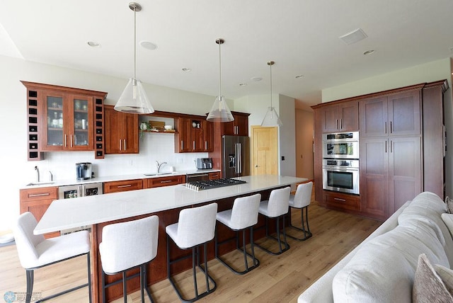 4703 Woodhaven St S, Fargo, ND 58104 - kitchen with appliances with stainless steel finishes, open floor plan, glass insert cabinets, light wood-style flooring, and light countertops