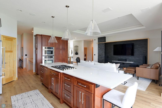 4703 Woodhaven St S, Fargo, ND 58104 - kitchen with appliances with stainless steel finishes, light wood-type flooring, open floor plan, a center island, and light countertops