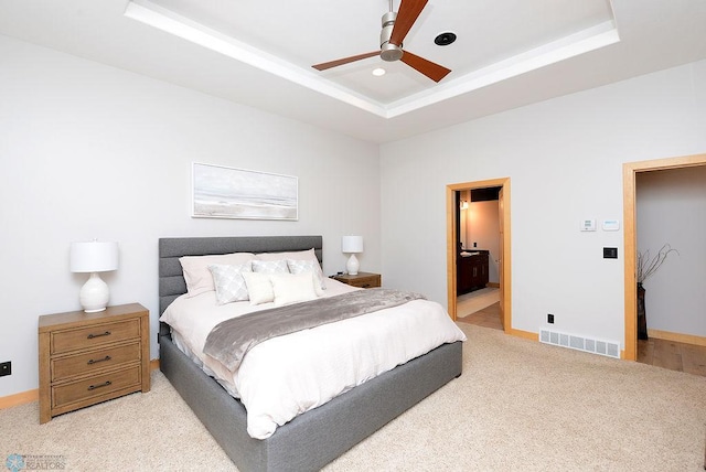 4703 Woodhaven St S, Fargo, ND 58104 - bedroom featuring a raised ceiling, light colored carpet, connected bathroom, and a ceiling fan