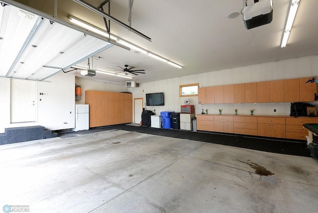 4703 Woodhaven St S, Fargo, ND 58104 - garage with a garage door opener, freestanding refrigerator, and a ceiling fan
