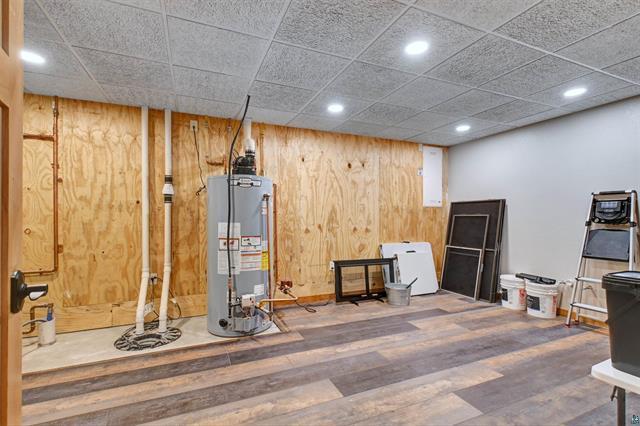 12207 Railroad Rd, Lake Nebagamon, WI 54849 - finished basement featuring gas water heater, wood finished floors, refrigerator, wooden walls, and recessed lighting