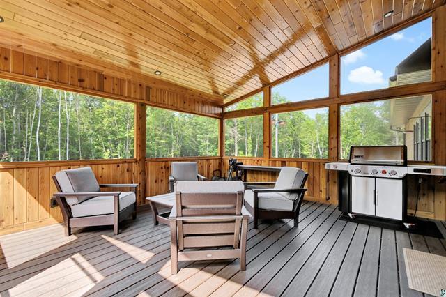12207 Railroad Rd, Lake Nebagamon, WI 54849 - sunroom / solarium with a deck, an outdoor living space, vaulted ceiling, wooden walls, and hardwood / wood-style flooring
