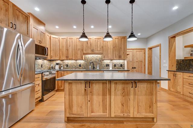 12207 Railroad Rd, Lake Nebagamon, WI 54849 - kitchen featuring appliances with stainless steel finishes, a kitchen island, decorative backsplash, light wood-style floors, and recessed lighting