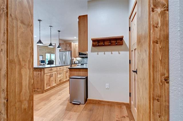 12207 Railroad Rd, Lake Nebagamon, WI 54849 - kitchen with freestanding refrigerator, light wood finished floors, tasteful backsplash, dark countertops, and hanging light fixtures