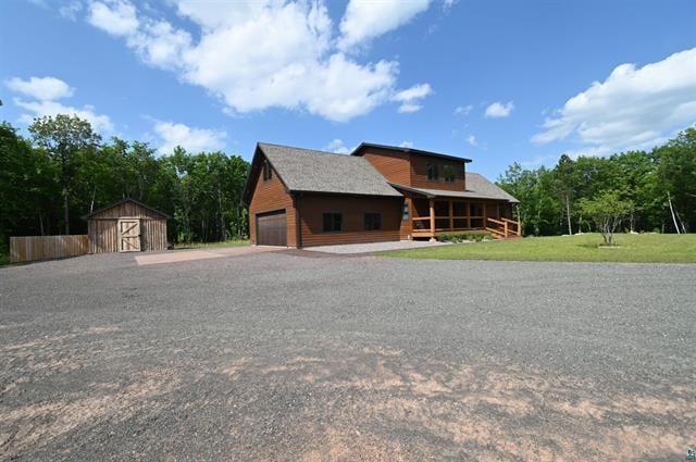 12207 Railroad Rd, Lake Nebagamon, WI 54849 - rustic home featuring a storage unit, driveway, and a front yard