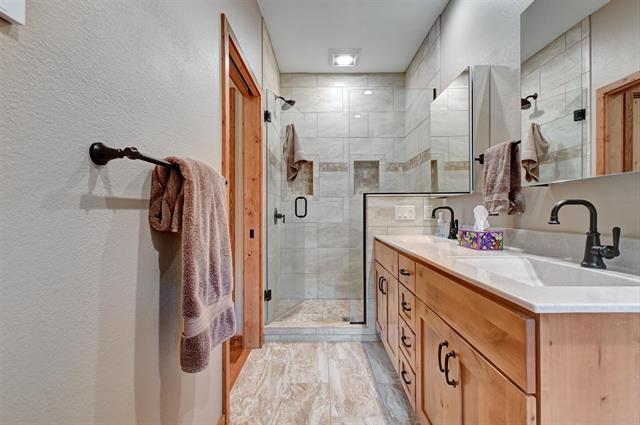 12207 Railroad Rd, Lake Nebagamon, WI 54849 - bathroom with a shower stall, double vanity, and a textured wall