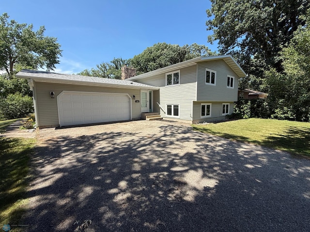 1303 Duluth Ave N, Thief River Falls, MN 56701 - tri-level home with asphalt driveway, a chimney, a garage, and a front lawn