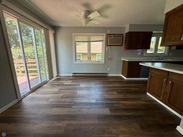 1303 Duluth Ave N, Thief River Falls, MN 56701 - kitchen featuring a baseboard radiator, dark wood-style flooring, light countertops, a textured ceiling, and a wall unit AC