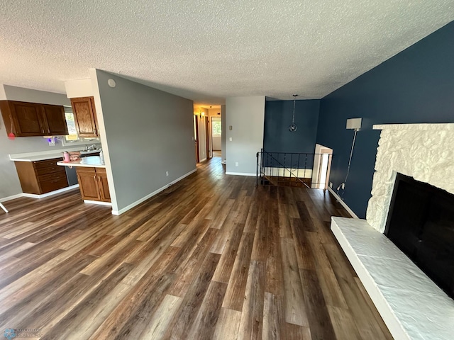 1303 Duluth Ave N, Thief River Falls, MN 56701 - unfurnished living room with a textured ceiling, dark wood-style flooring, and a stone fireplace