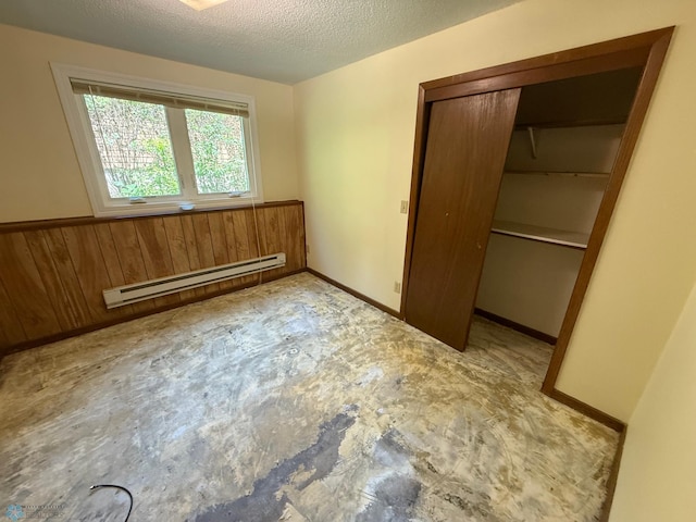 1303 Duluth Ave N, Thief River Falls, MN 56701 - unfurnished bedroom with a baseboard heating unit, a closet, a textured ceiling, wood walls, and wainscoting