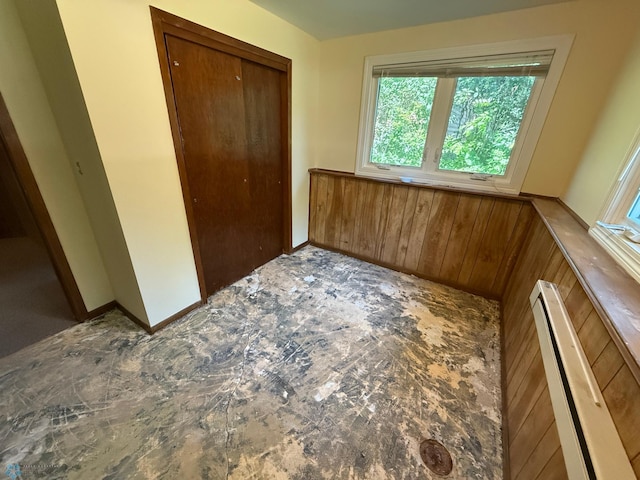1303 Duluth Ave N, Thief River Falls, MN 56701 - unfurnished bedroom featuring a baseboard radiator, a closet, and wood walls