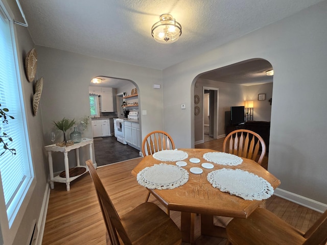 818 Kenwood St, Alexandria, MN 56308 - dining area with arched walkways, wood finished floors, a textured ceiling, and a baseboard heating unit