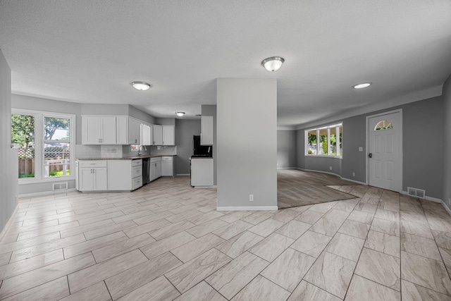 4801 Louisiana Ave N, Crystal, MN 55428 - kitchen featuring open floor plan, stainless steel dishwasher, white cabinetry, and plenty of natural light