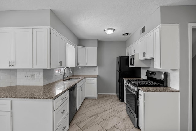 4801 Louisiana Ave N, Crystal, MN 55428 - kitchen featuring stainless steel appliances, white cabinetry, backsplash, dark stone countertops, and a textured ceiling