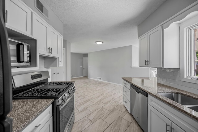 4801 Louisiana Ave N, Crystal, MN 55428 - kitchen featuring stainless steel appliances, stone counters, healthy amount of natural light, white cabinets, and a textured ceiling