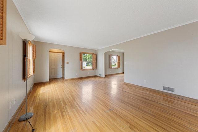 215 Plainview St, Owatonna, MN 55060 - unfurnished living room featuring arched walkways, light wood-type flooring, and crown molding
