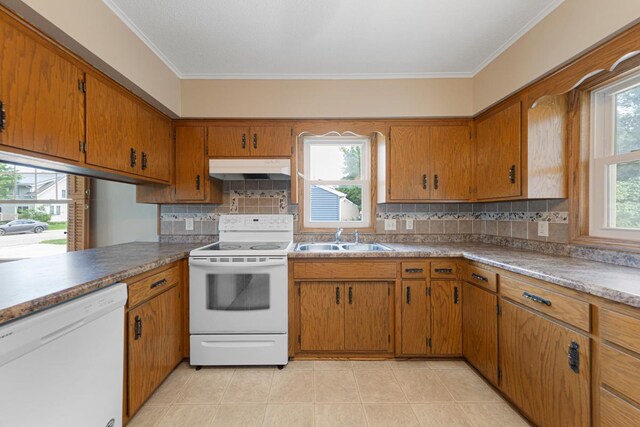 215 Plainview St, Owatonna, MN 55060 - kitchen with white appliances, under cabinet range hood, brown cabinets, crown molding, and decorative backsplash