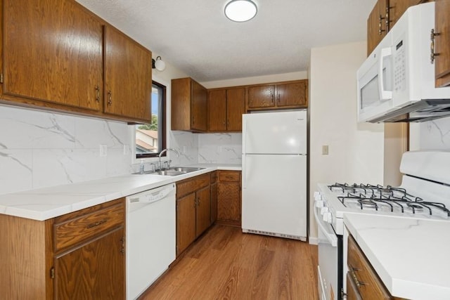 8983 Vinewood Ln N, Maple Grove, MN 55369 - kitchen with white appliances, light wood-style floors, decorative backsplash, light countertops, and brown cabinetry