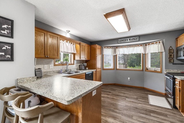 5830 Forest Boulevard Trl, Wyoming, MN 55092 - kitchen with appliances with stainless steel finishes, a peninsula, brown cabinetry, dark wood-style flooring, and light countertops