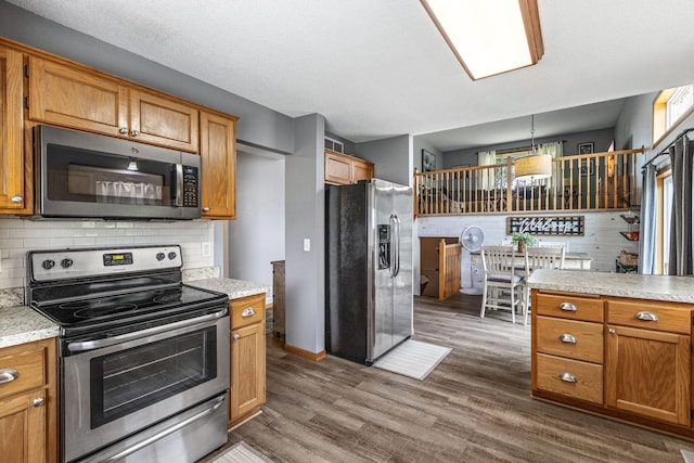 5830 Forest Boulevard Trl, Wyoming, MN 55092 - kitchen with stainless steel appliances, dark wood-style floors, decorative backsplash, light countertops, and brown cabinetry