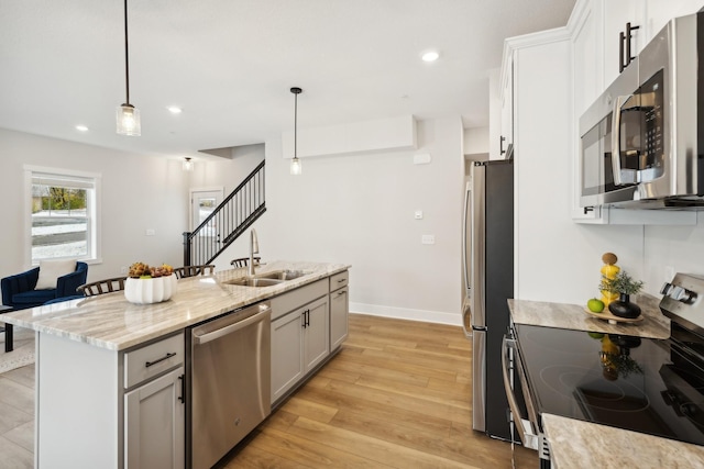 3401 Douglas Dr N, Crystal, MN 55422 - kitchen featuring appliances with stainless steel finishes, light wood-style floors, light stone counters, a kitchen island with sink, and recessed lighting