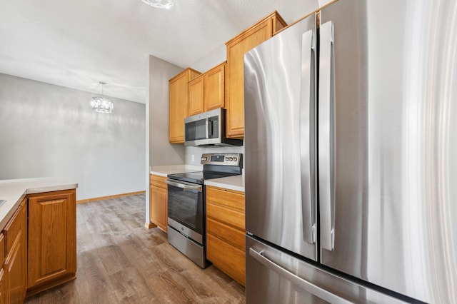886 Coon Rapids Boulevard Extension NW, Coon Rapids, MN 55433 - kitchen with appliances with stainless steel finishes, wood finished floors, light countertops, and a chandelier
