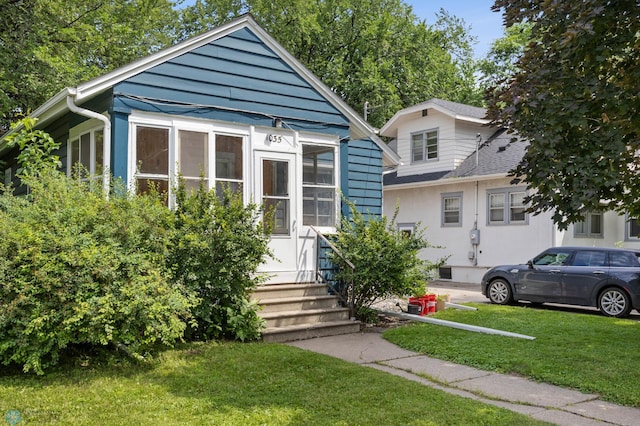 1035 University Dr N, Fargo, ND 58102 - bungalow-style house featuring a sunroom, a front yard, and roof with shingles