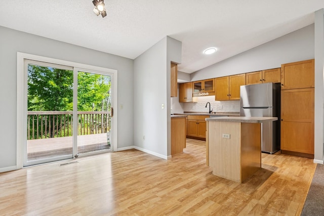 551 Townes Rd, Minnetonka, MN 55391 - kitchen featuring freestanding refrigerator, vaulted ceiling, a kitchen island, light wood-style flooring, and glass insert cabinets