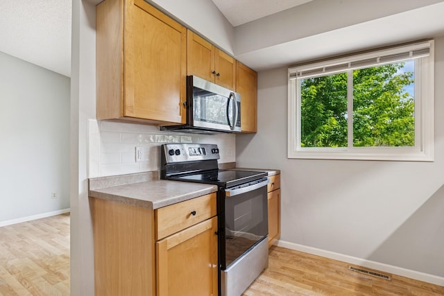 551 Townes Rd, Minnetonka, MN 55391 - kitchen with stainless steel appliances, light wood-style floors, tasteful backsplash, and light countertops