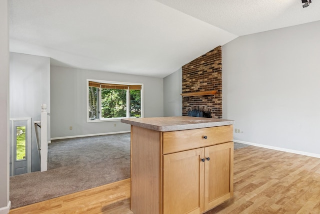 551 Townes Rd, Minnetonka, MN 55391 - kitchen with open floor plan, light brown cabinetry, vaulted ceiling, a fireplace, and light wood-style floors