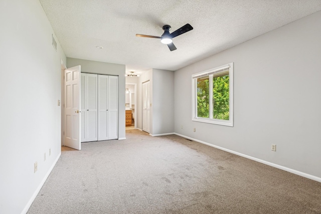 551 Townes Rd, Minnetonka, MN 55391 - unfurnished bedroom featuring light colored carpet, a textured ceiling, multiple closets, connected bathroom, and a ceiling fan