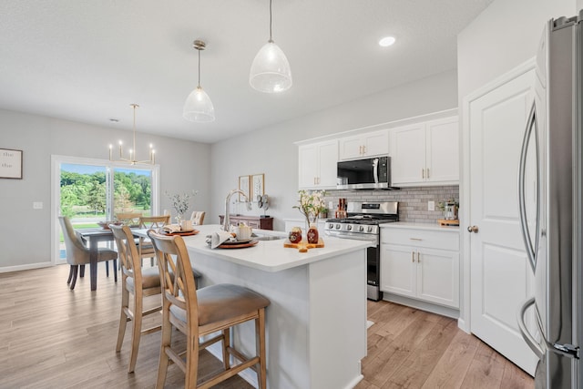 2452 Greenbriar Ln, Buffalo, MN 55313 - kitchen with appliances with stainless steel finishes, light wood-style floors, light countertops, a kitchen breakfast bar, and white cabinetry