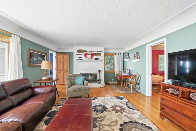 1276 County Rd Unit G, Milltown, WI 54858 - living room with a textured ceiling, wood finished floors, and a brick fireplace