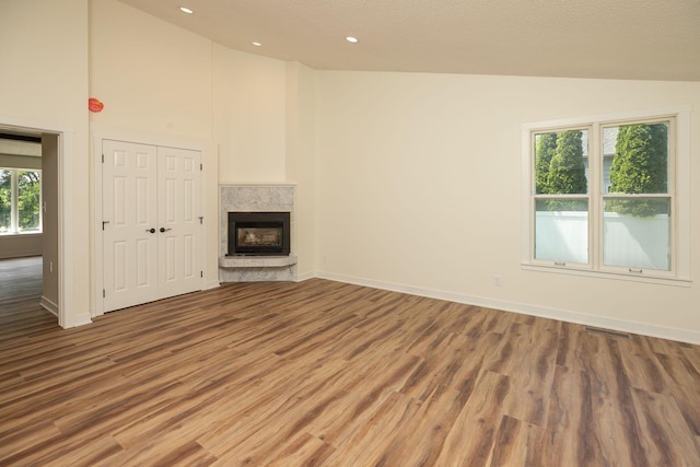405 River St SW, Chatfield, MN 55923 - unfurnished living room featuring wood finished floors, a fireplace with raised hearth, high vaulted ceiling, and recessed lighting