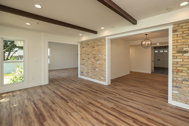405 River St SW, Chatfield, MN 55923 - spare room with wood finished floors, beamed ceiling, brick wall, a chandelier, and recessed lighting