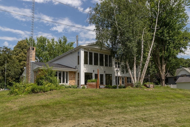 405 River St SW, Chatfield, MN 55923 - neoclassical home with brick siding, a sunroom, a chimney, and a front yard