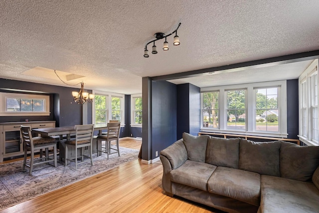 3979 Reservoir Blvd, Columbia Heights, MN 55421 - living room featuring a chandelier, light wood-style floors, a textured ceiling, and healthy amount of natural light