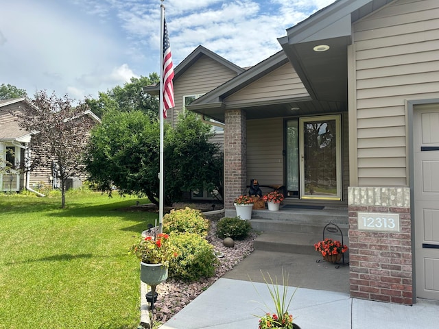 12313 Ilex St NW, Coon Rapids, MN 55448 - property entrance featuring a lawn, covered porch, and brick siding