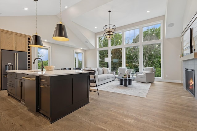 2850 Victoria St N, Roseville, MN 55113 - kitchen featuring high vaulted ceiling, stainless steel appliances, light countertops, a tile fireplace, and hanging light fixtures