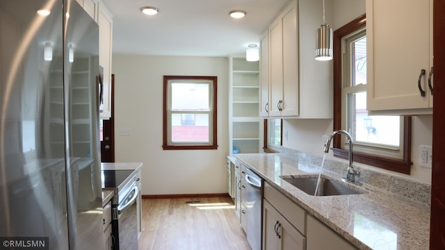 6007 Vincent Ave N, Brooklyn Center, MN 55430 - kitchen featuring appliances with stainless steel finishes, light wood-style floors, light stone countertops, and white cabinetry